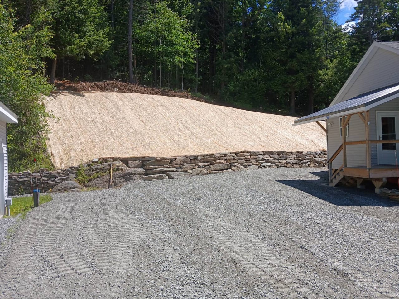 Stabilized slope with stone retaining wall and fresh gravel drive